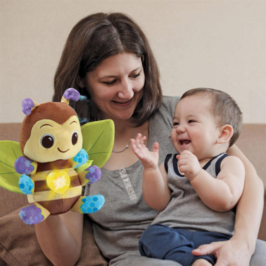 A colorful VTech Busy Musical Bee toy with yellow plush body, blue crinkle wings, and a green easy-grip handle with beads.