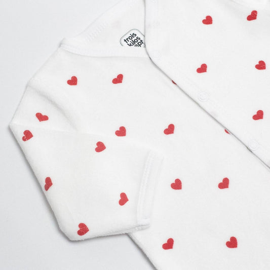 An ecru-colored long-sleeve baby sleepsuit with a red heart pattern by Trois Kilos Sept, sized for 6 months.