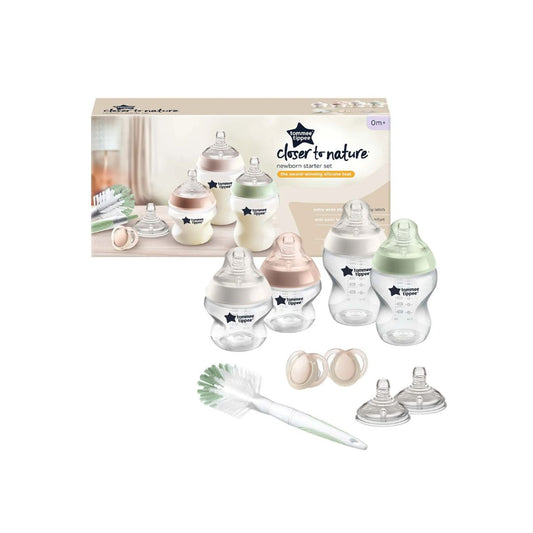 Collection of Tommee Tippee baby bottles, pacifiers, and a cleaning brush on a white background