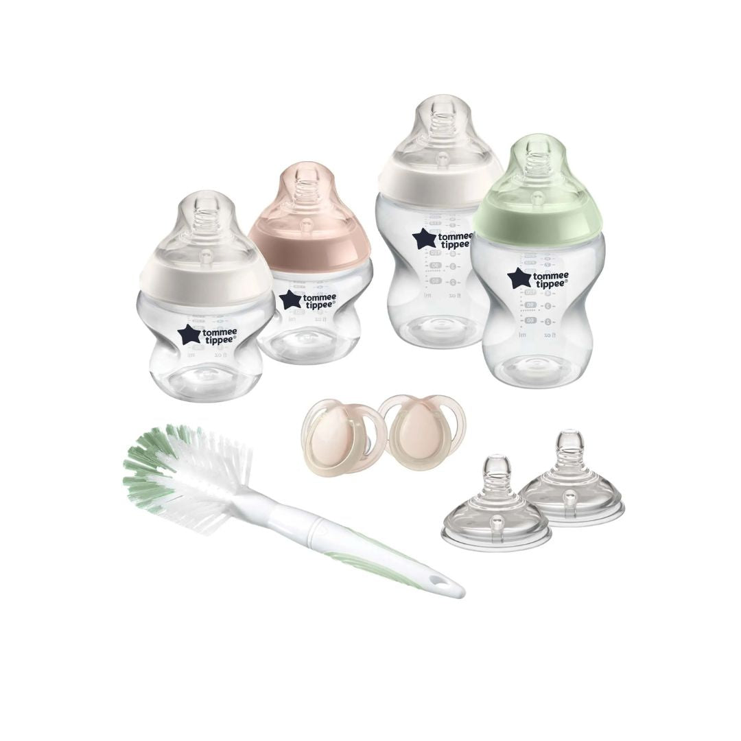 Collection of Tommee Tippee baby bottles, pacifiers, and a cleaning brush on a white background
