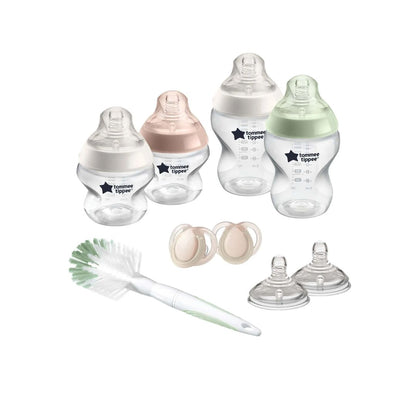 Collection of Tommee Tippee baby bottles, pacifiers, and a cleaning brush on a white background