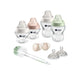 Collection of Tommee Tippee baby bottles, pacifiers, and a cleaning brush on a white background