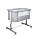 Asalvo Smart co-sleeping crib in grey with wood-effect legs and a mesh side window next to a parents' bed.