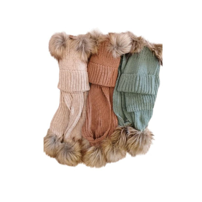 Three sets of baby knit beanies and matching scarves in cream, tan, and green with large faux fur pom-poms.