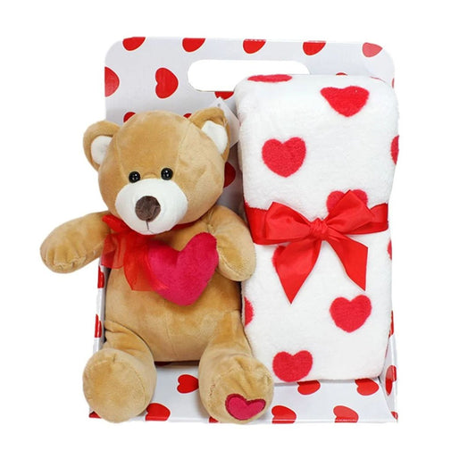 Brown Valentine's Day teddy bear holding a heart, paired with a red and white heart-patterned plush blanket.