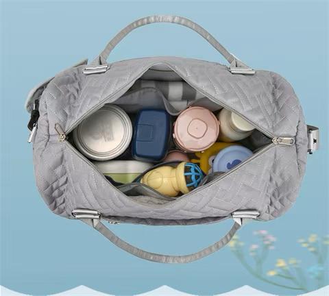 Gray quilted duffel bag with silver accents on a white background