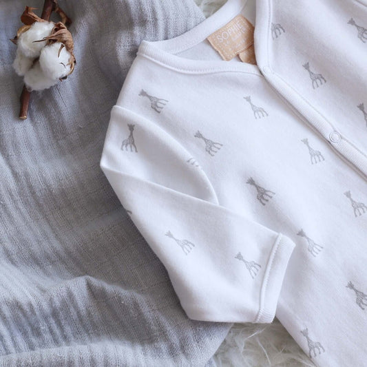 A pure white long-sleeve cotton sleepsuit for babies by Sophie la Girafe, featuring a small embroidered giraffe on the chest.